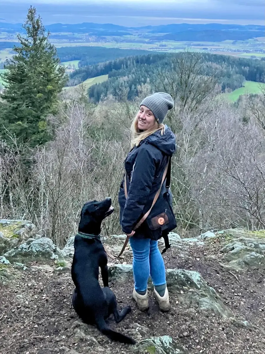 Nadine Roth mit ihrem schwarzen Labrador auf einer Anhöhe mit Blick über die Oberpfalz